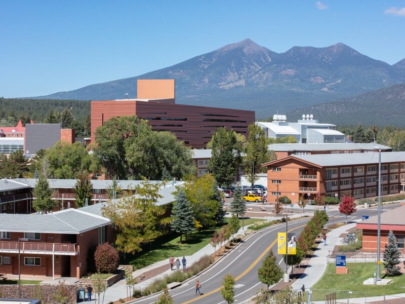 Flagstaff campus overview showing students crossing the street and the San Francisco peaks in background.
