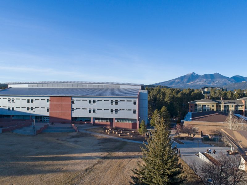Drone photo showing The W A Franke College of Business from behind with the San Francisco peaks in the background.