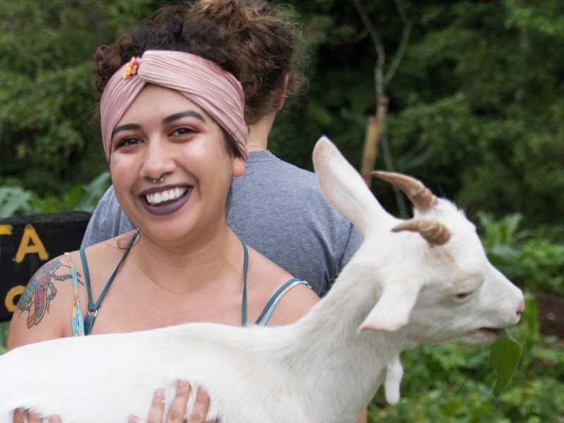 NAU study abroad student in a forest holding a goat.