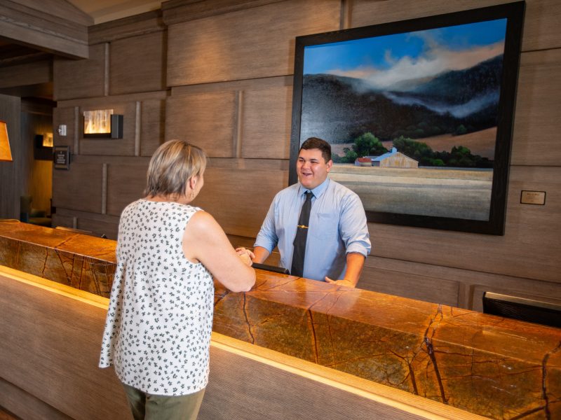 Student assisting a customer at a hotel front desk.