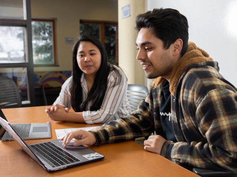Two students looking at a laptop in the advising office.