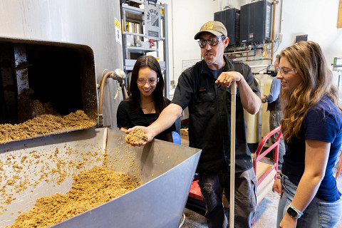 Mother Road Brewing employee shows two individuals steps of the beer making process.