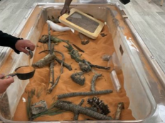 picture of red sand table with sticks, rocks, sifters and scoops
