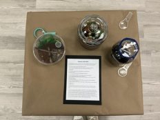 A table holding a paper and three jars of dit and rocks. The paper explains what children did with the dirt samples.