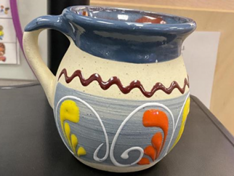 mug made in Mexico, blue rim with tan body, featuring brown, yellow, orange, and white swirls.