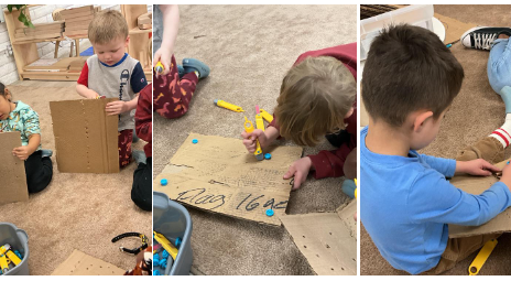 a child on the ground using child-sized cutting tools to cut and screw into cardboard.