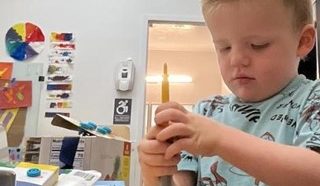 A child constructing with recyclable materials, with tape and egg cartons.