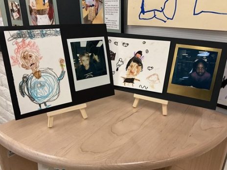 Display of self portraits and polaroid photos created by two children.