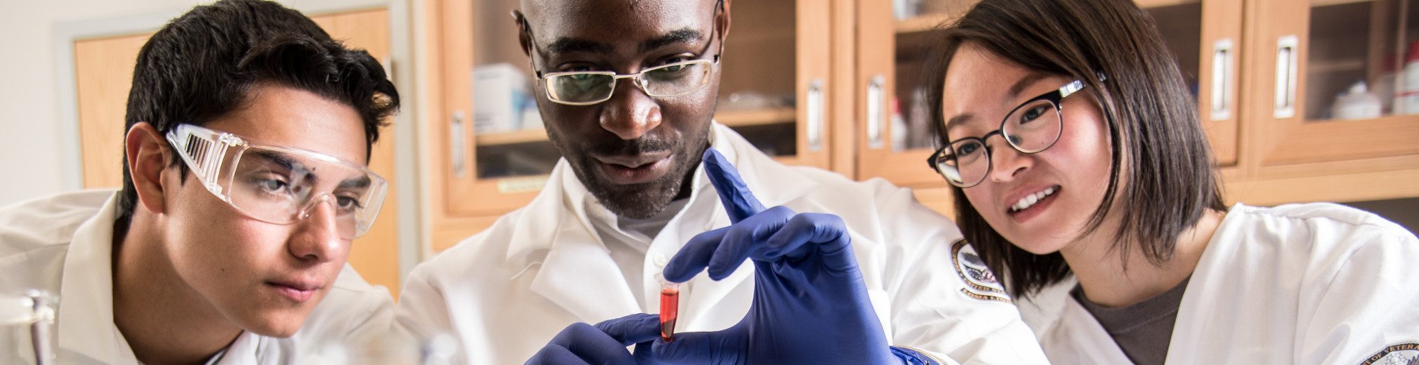 Students in lab coats examining a vial