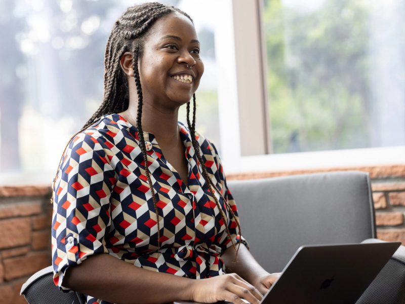 A Northern Arizona University student smiling while using a laptop computer.