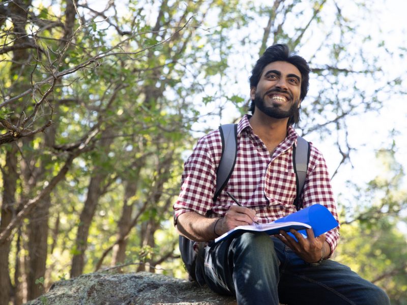 A Northern Arizona University student sitting outside with a book.