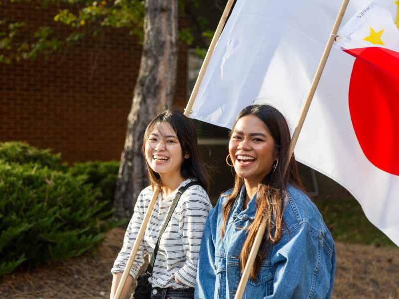 Two N A U students holding flags during the Parade of Nations.