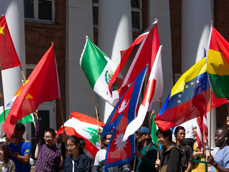 Students walking outside with international flags.