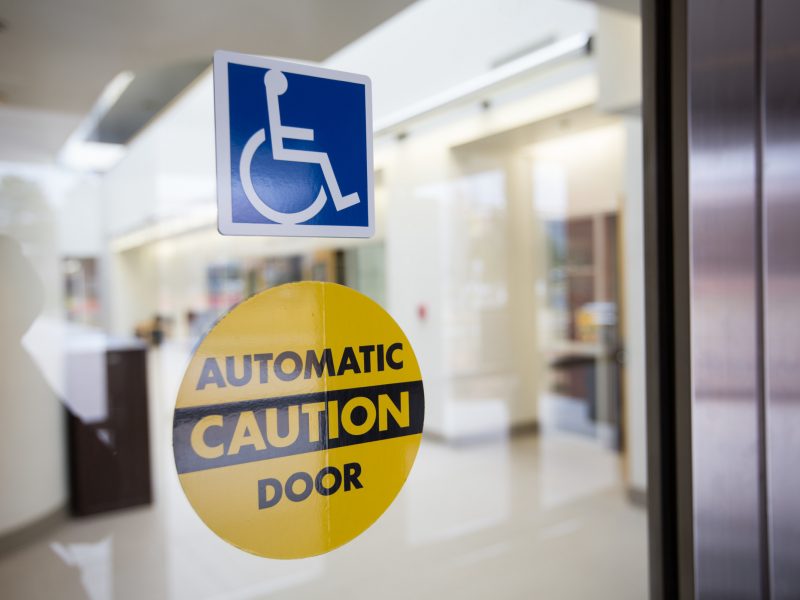 Handicapped logo and automatic door signs on a glass door.