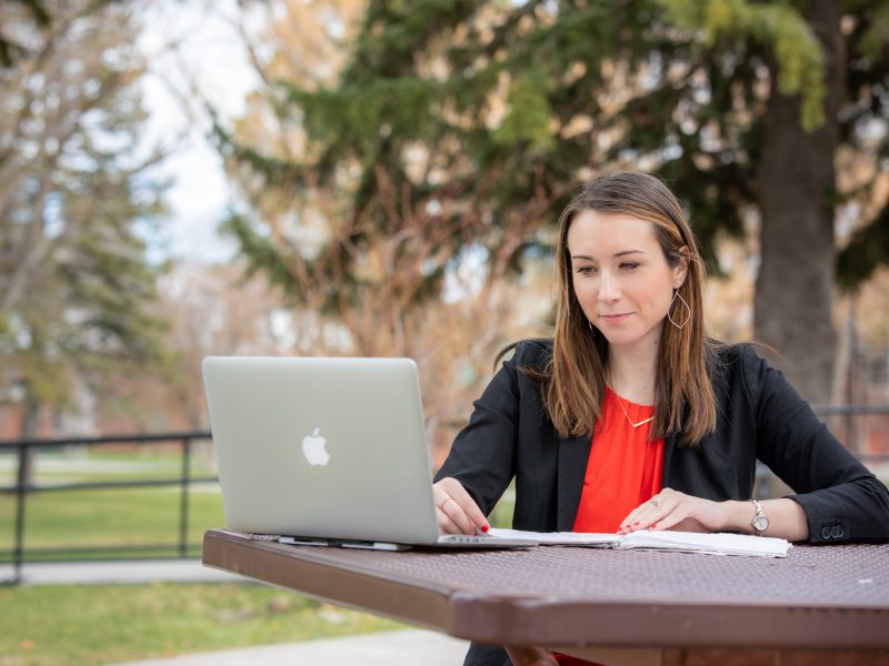 A student studying on her laptop outside.