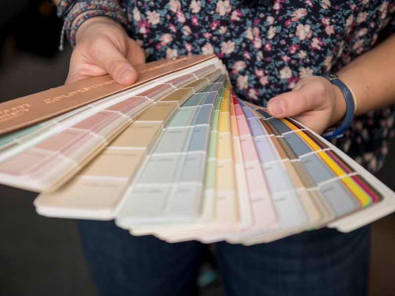 A person holding many paper color palettes.