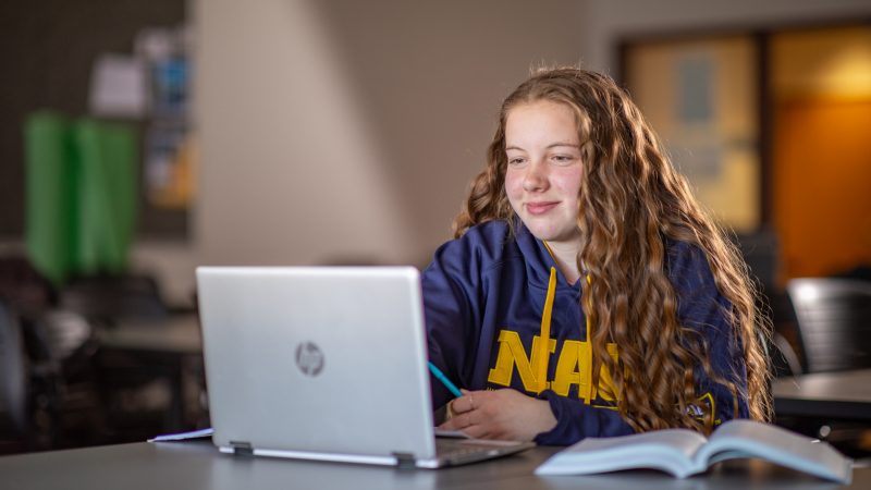 N A U student Gabrielle Nevers works on laptop smiling.