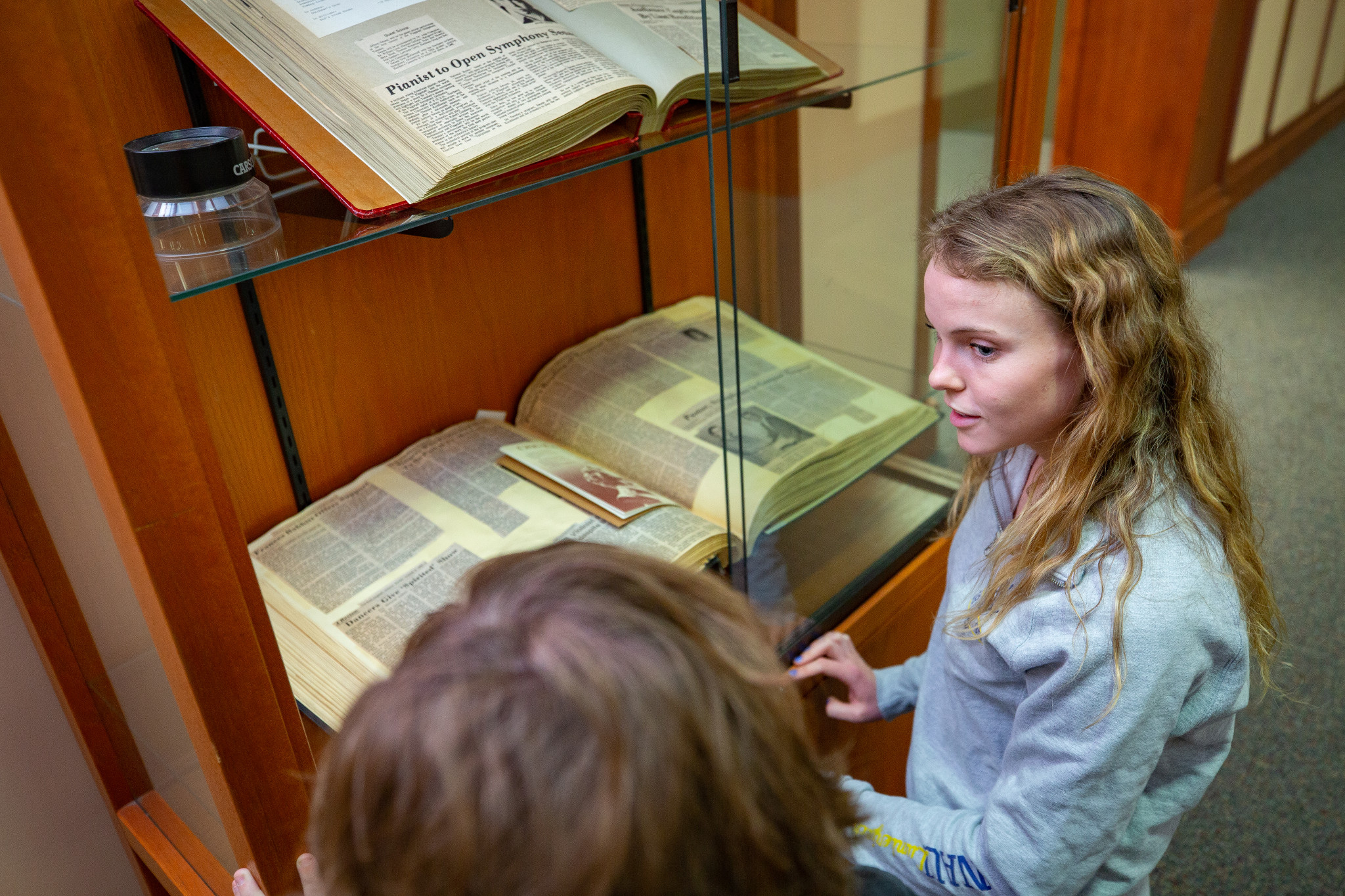 Students read historic textbook in glass display