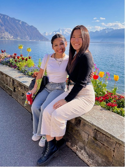 Ana and a friend sitting on a stone wall in front of a lake and tulips.