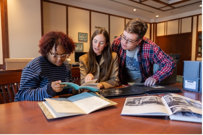 Three students look at books in Cline Library special collections.