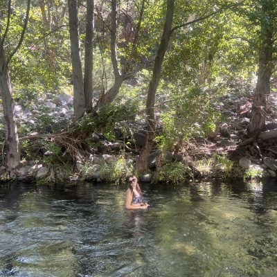 Cierra standing in creek under trees