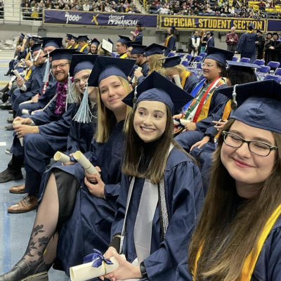 undergrads from history department smile and pose from tehir row of seasts at commencement