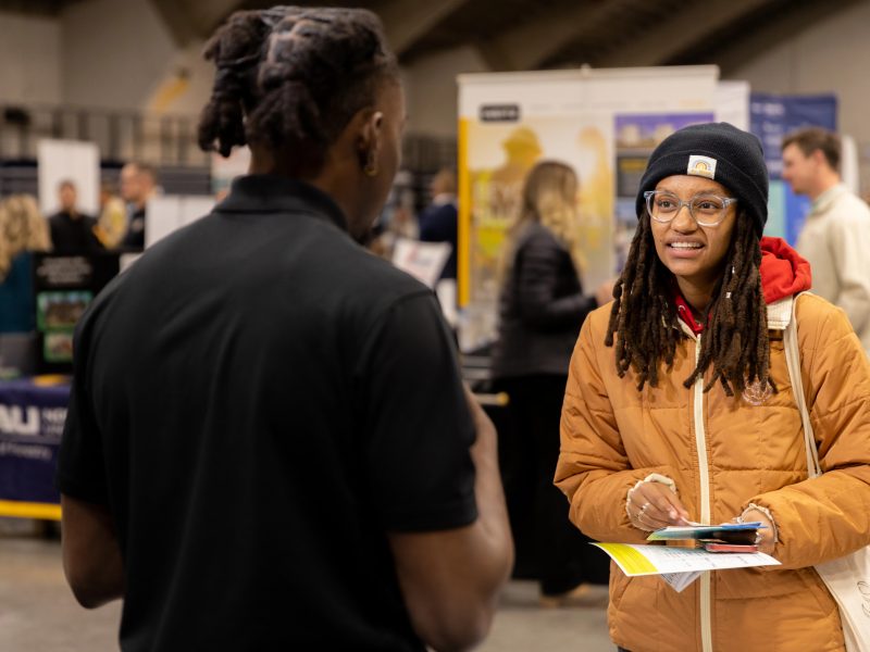 A student talks to a business representative at a N A U career fair.