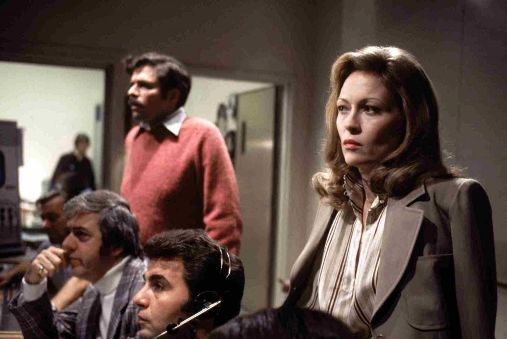 Scene from "Network "with Faye Dunaway  - 1970's newsroom with four people watching from behind scenes looking serious