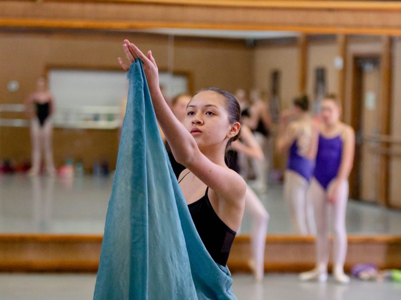 Ballet student holding up the tip of her skirt as part of a rehearsal.