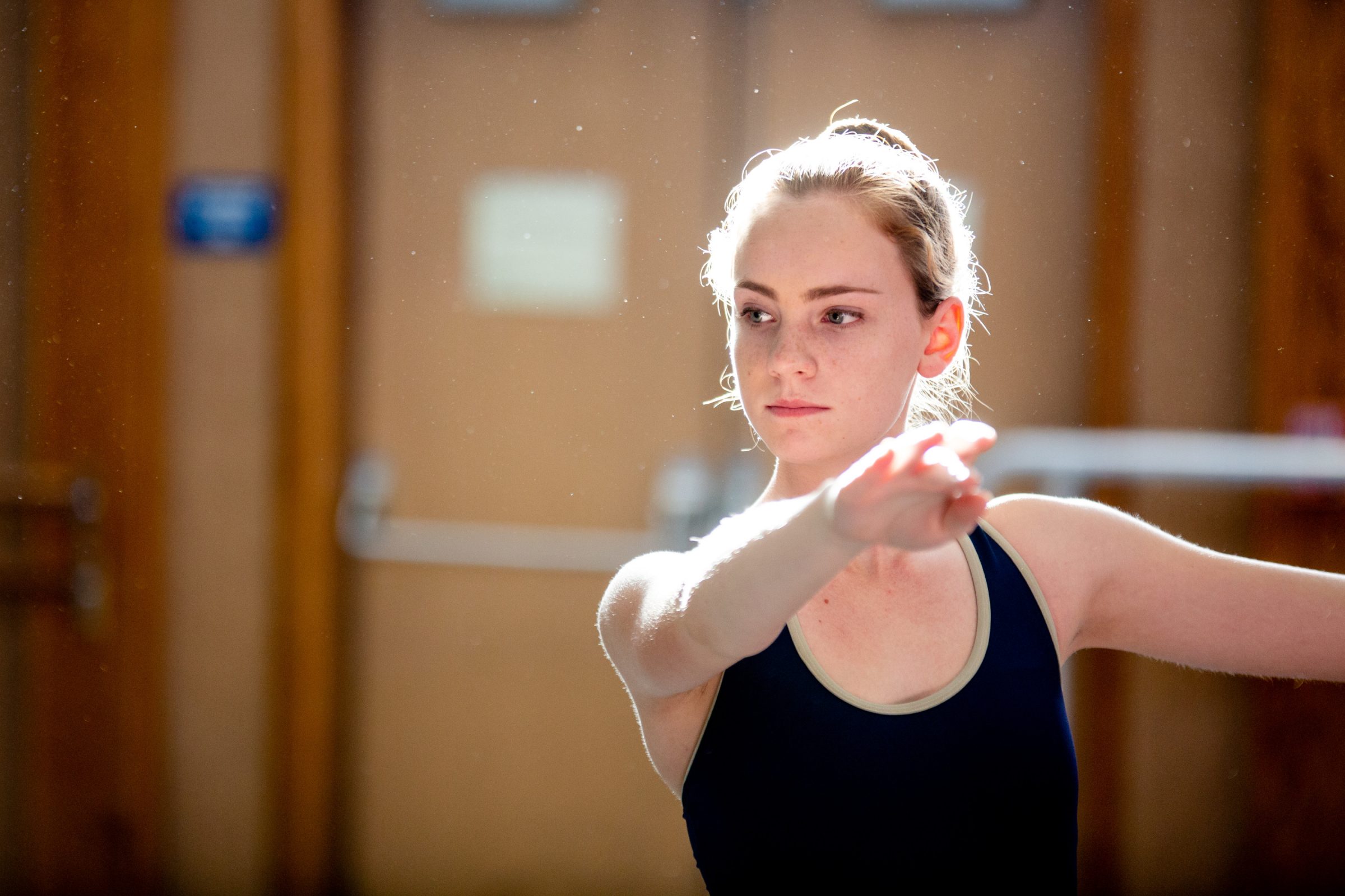 Female dance student holding arm out and focusing on her dance practice.