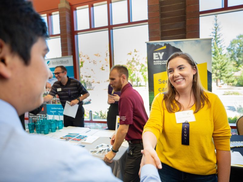 Two people shaking hands at a career expo.