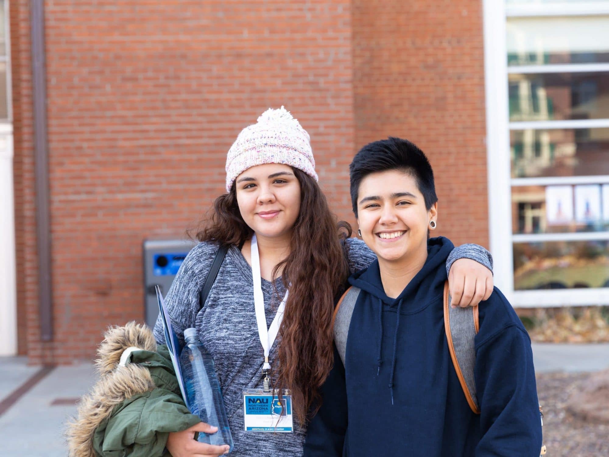 Dos estudiantes sonríen y miran a la cámara en el campus de NAU.