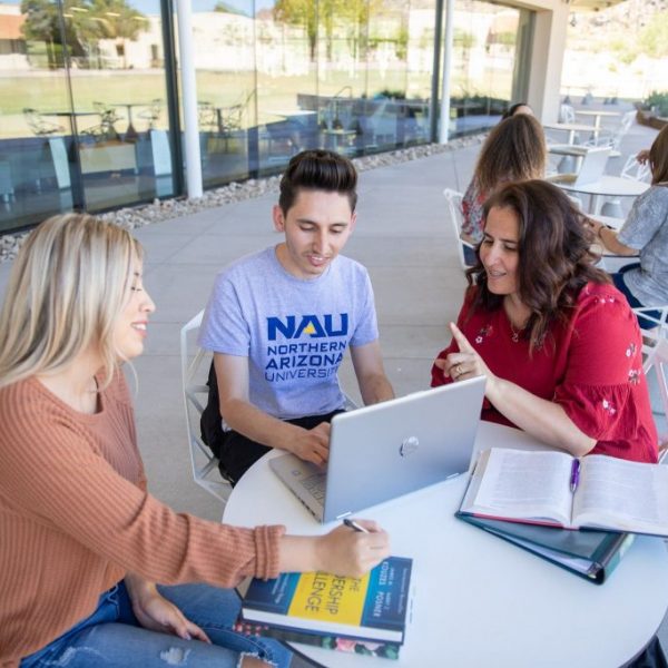 Tres personas trabajan juntas enfrente de una computadora portátil en un campus de NAU.