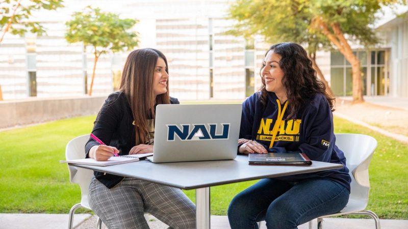 Dos estudiantes sentados enfrente de una computadora portátil en el campus de NAU-Yuma.