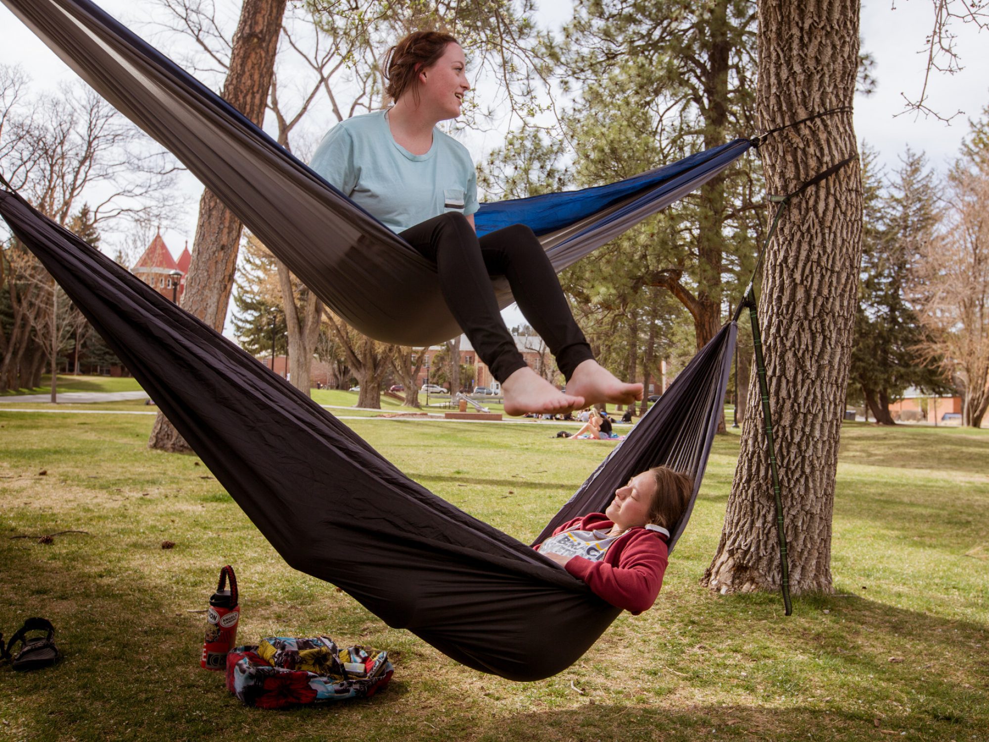 Dos estudiantes se relajan en hamacas en el patio norte de NAU.