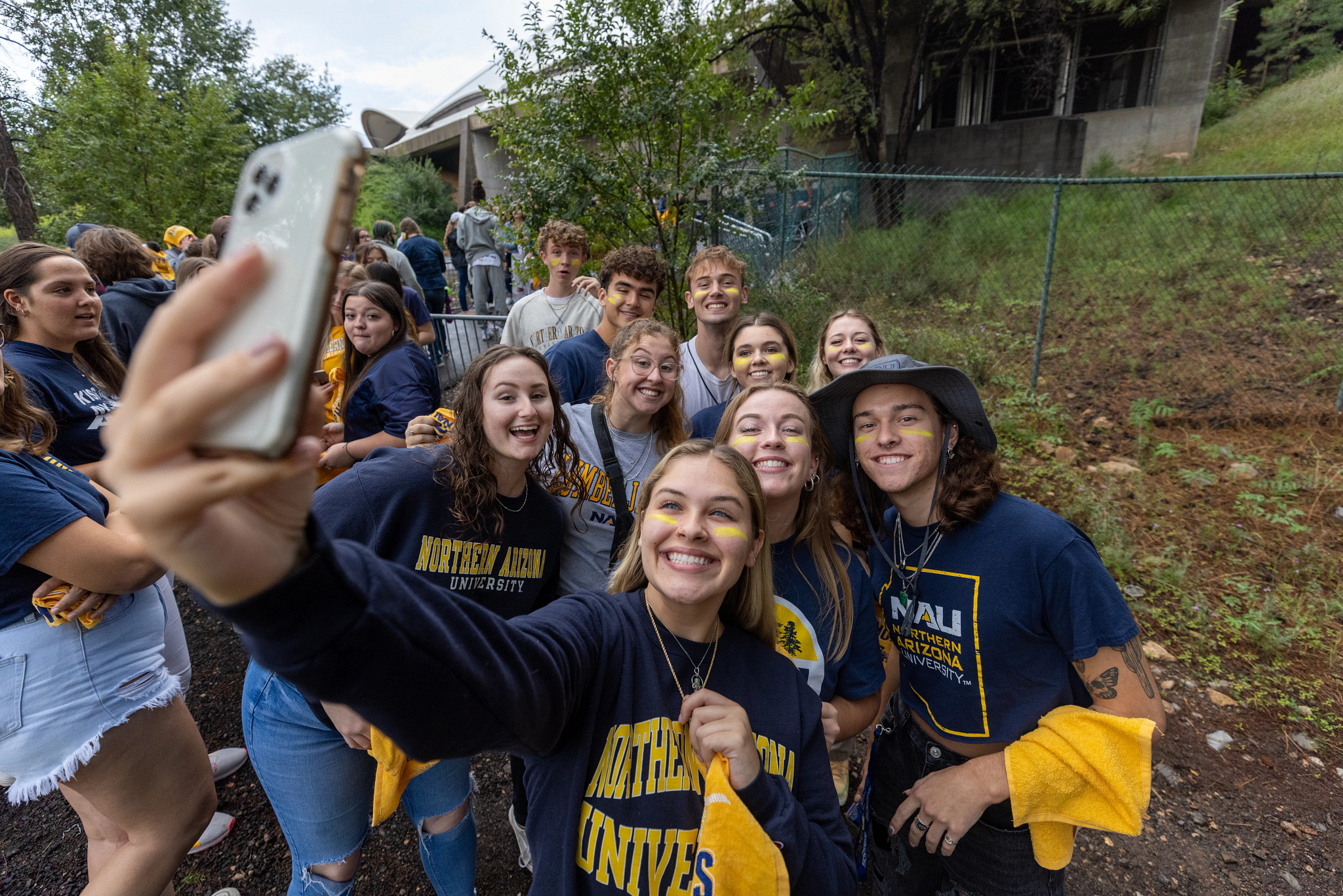 Un grupo de estudiantes de NAU con ropa de la marca NAU posan juntos para una selfie.