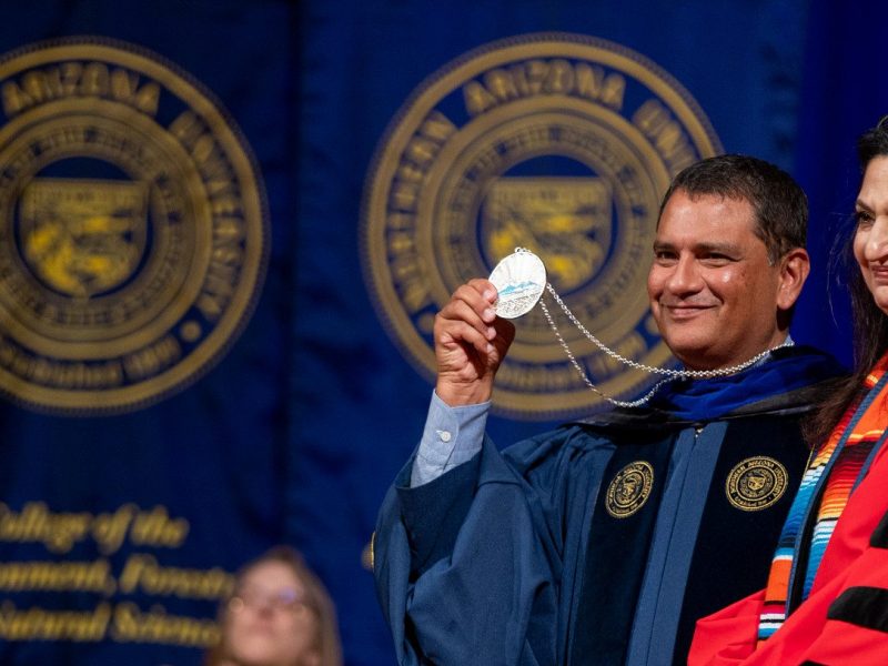Presidente José Luis Cruz Rivera de NAU demuestra una medalla durante la ceremonia de graduación.