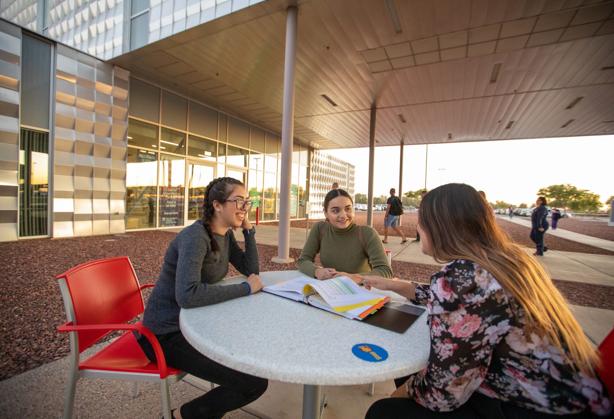 Tres estudiantes sentados alrededor de una mesa en el campus de NAU-Yuma estudiando.