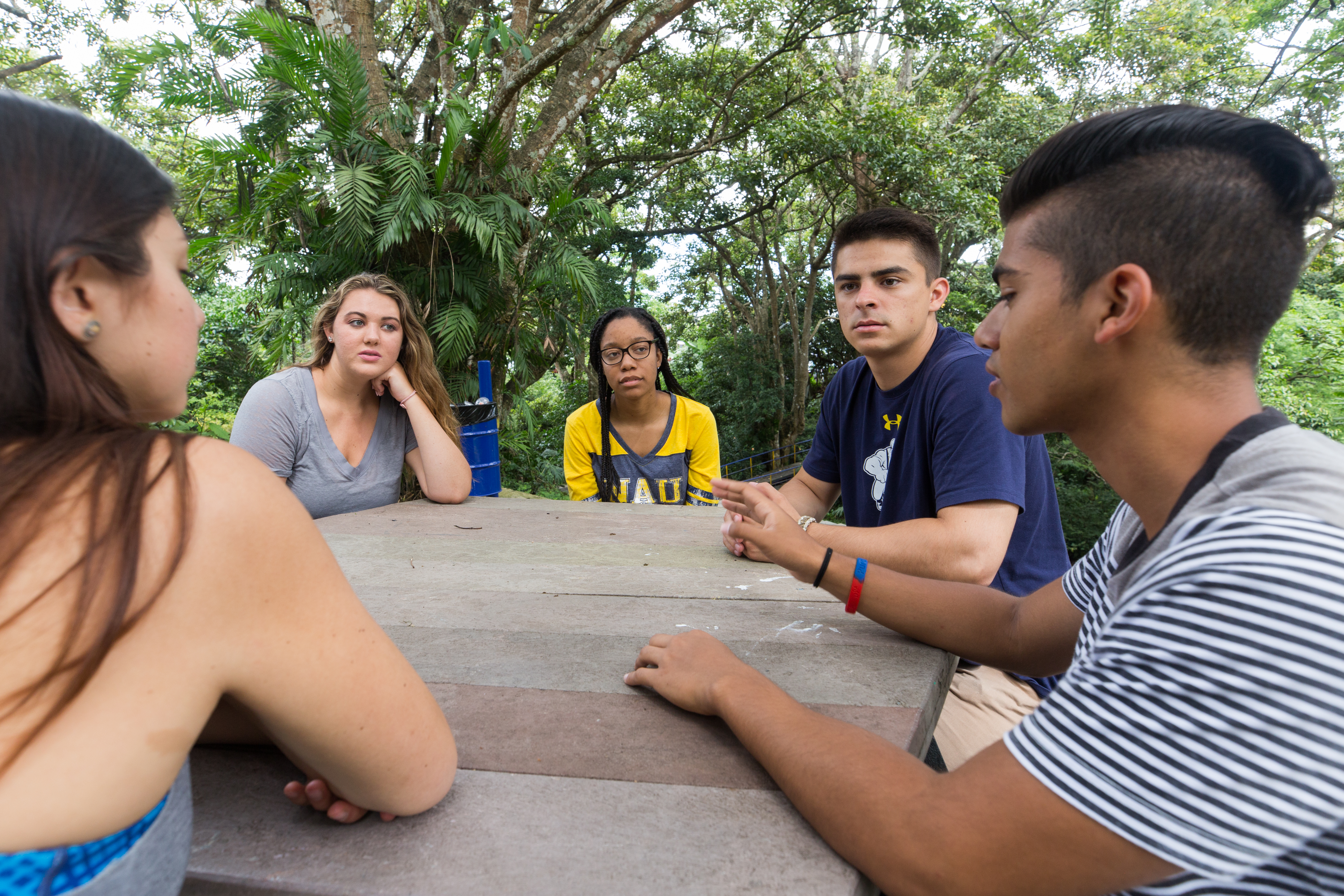 Un grupo de estudiantes de NAU se han sentado alrededor de una mesa y platican.