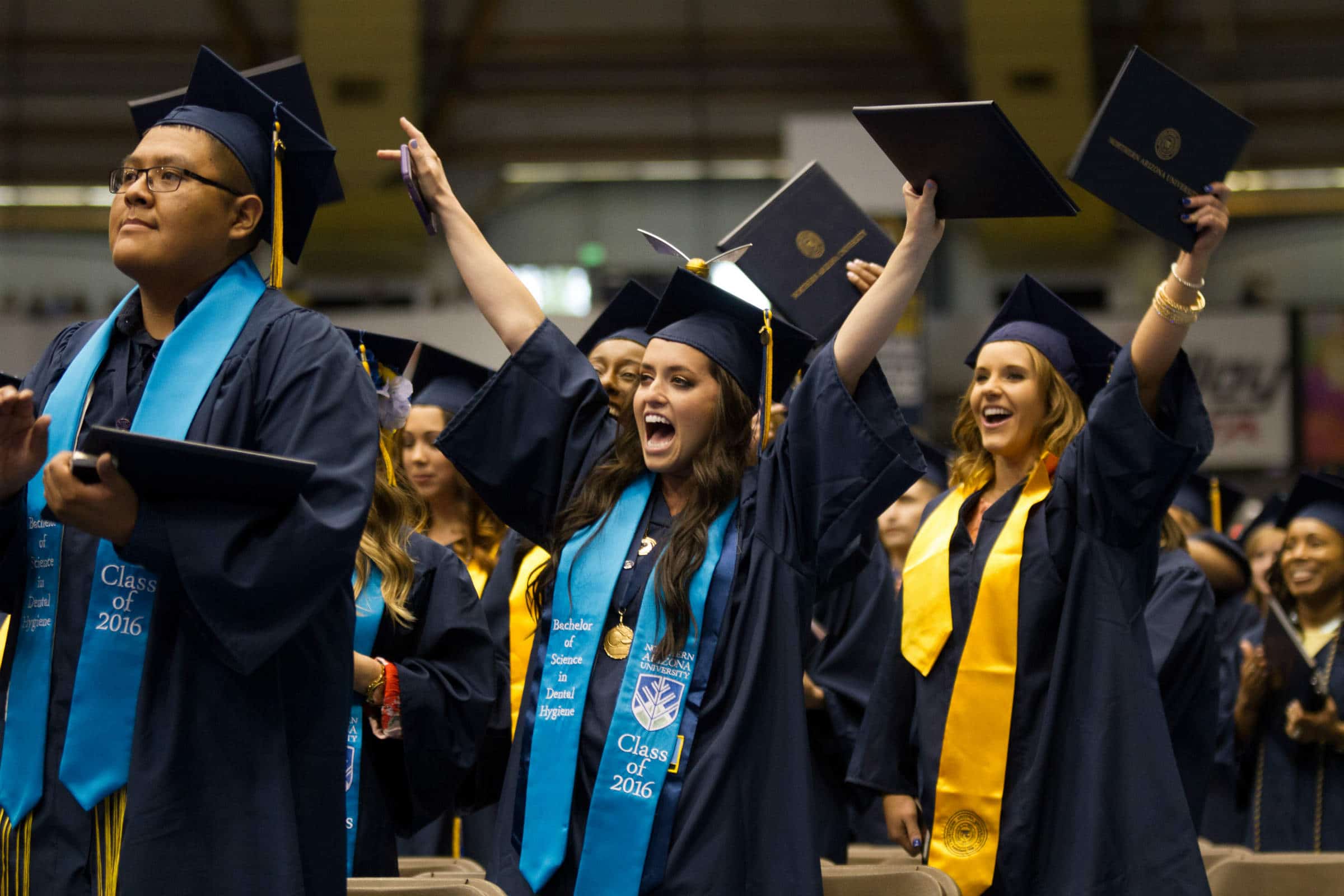 NAU graduates raise their diplomas in celebration.