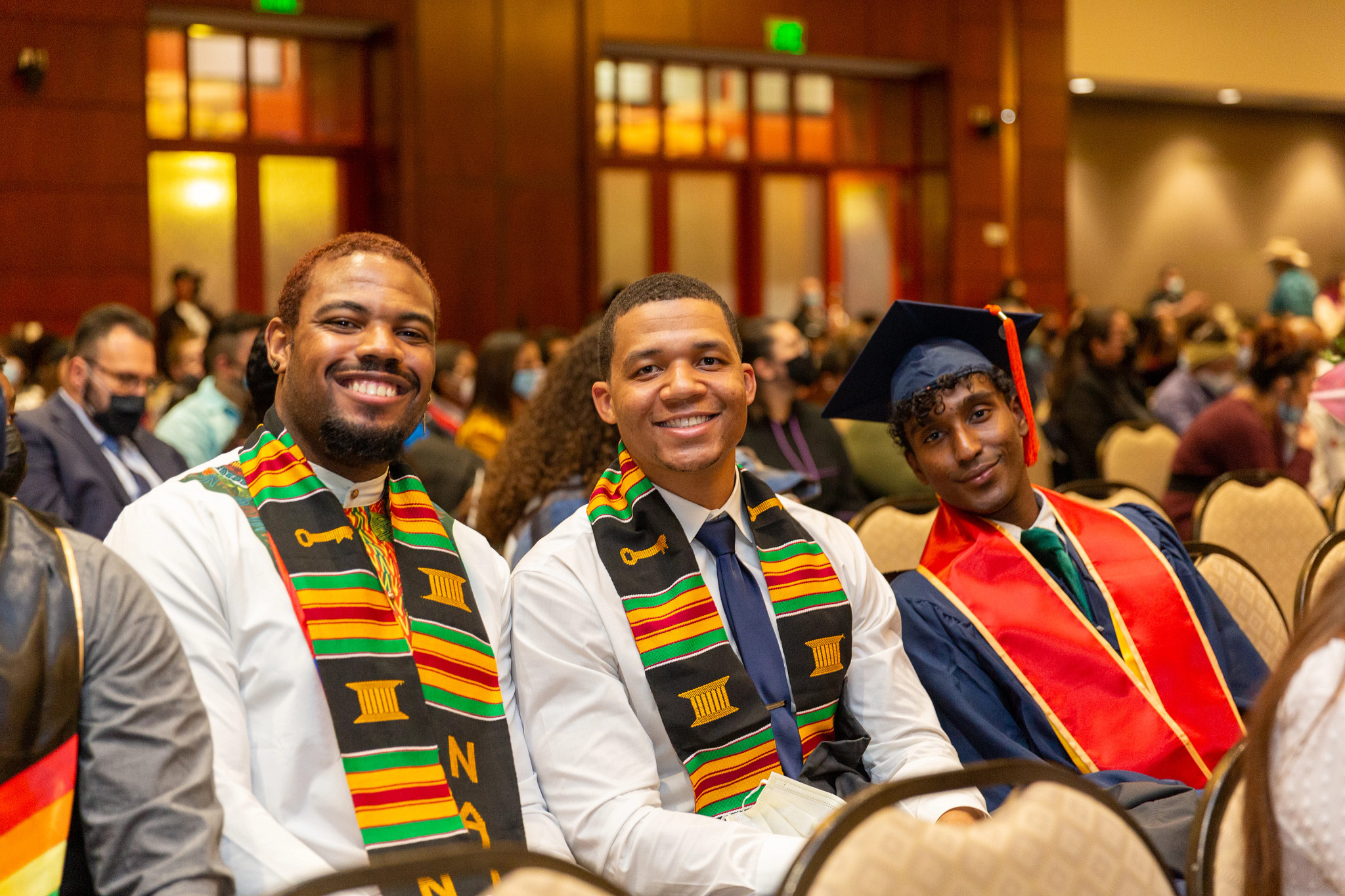 Three male NAU students wearing Lumberjacks of Inclusion stoles sitting at an event