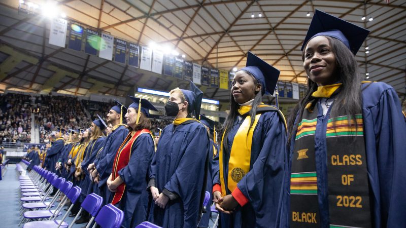 NAU grads wearing caps and gowns standing during the Commencement ceremony