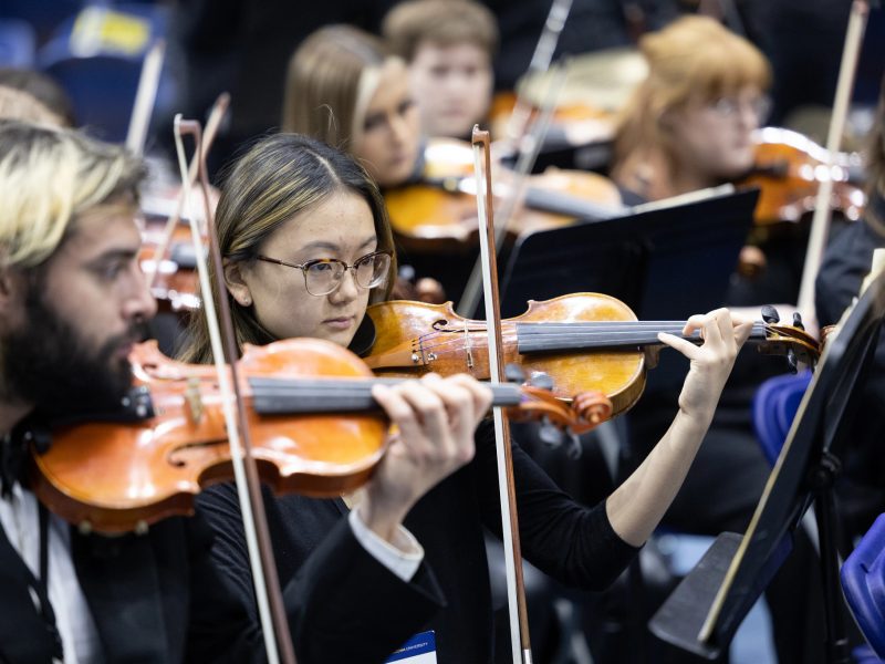 Violin section of the NAU orchestra performing.
