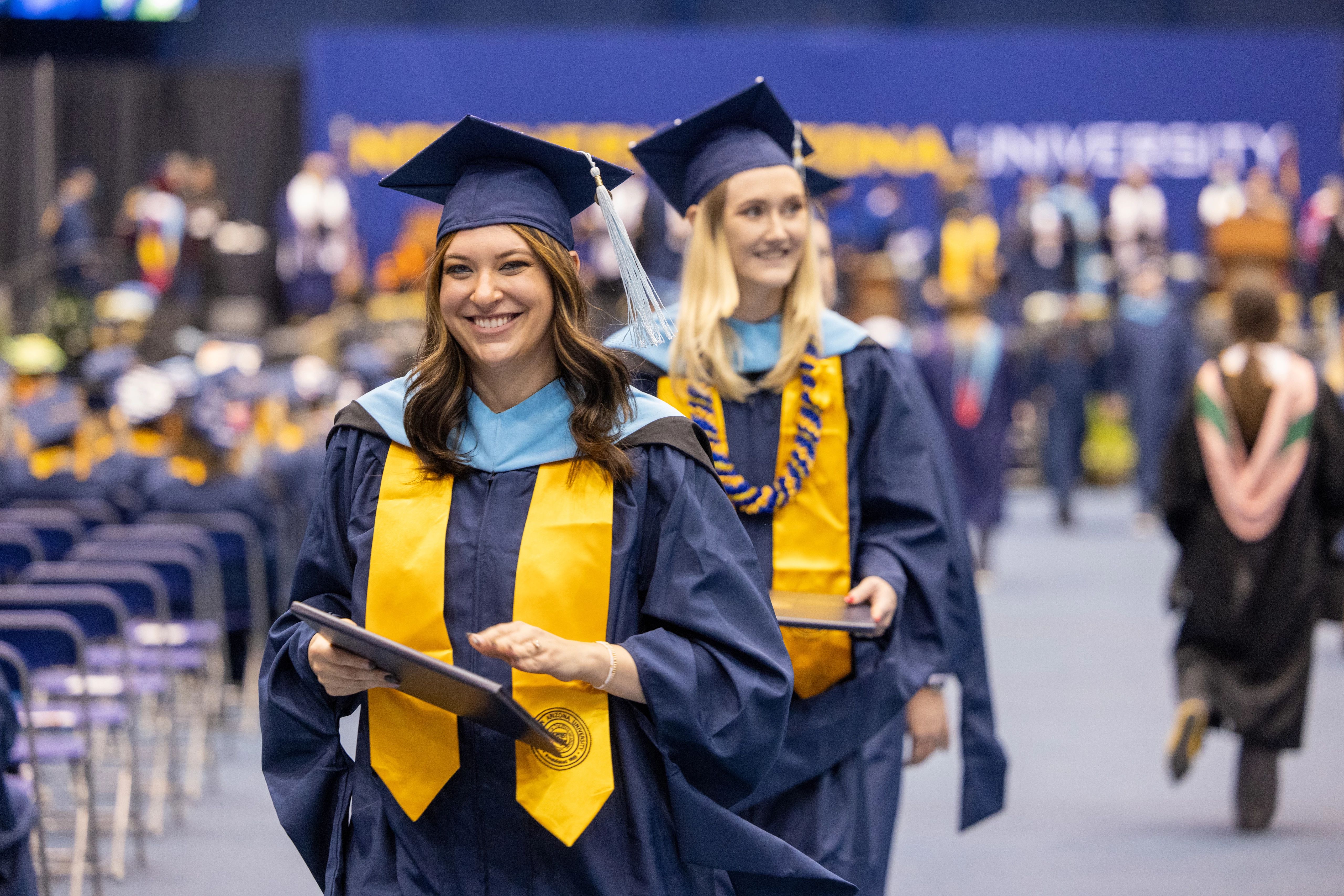 Female NAU students walking away from the stage after having received their diplomas