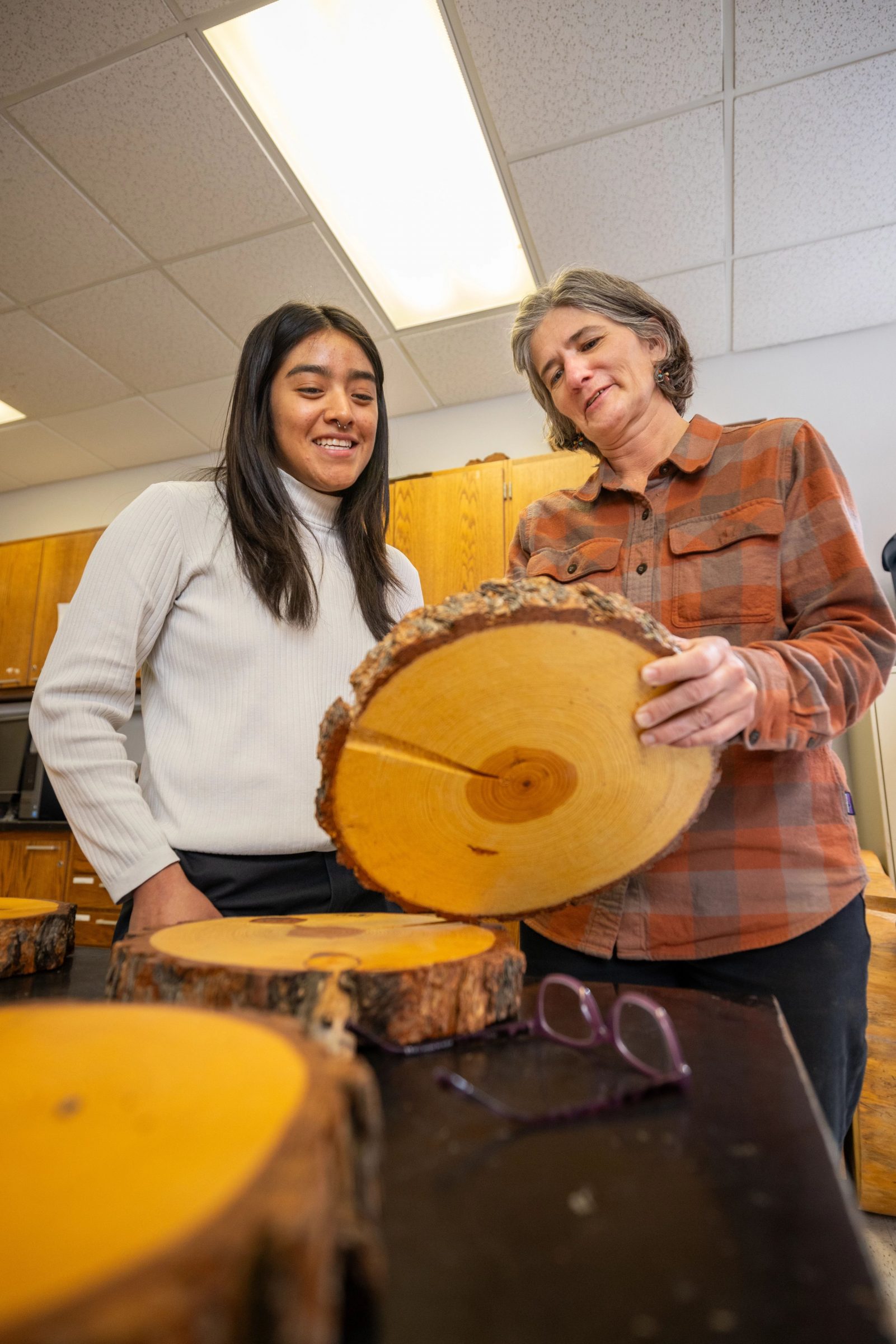 Professor and student studying tree trunk rings in classroom