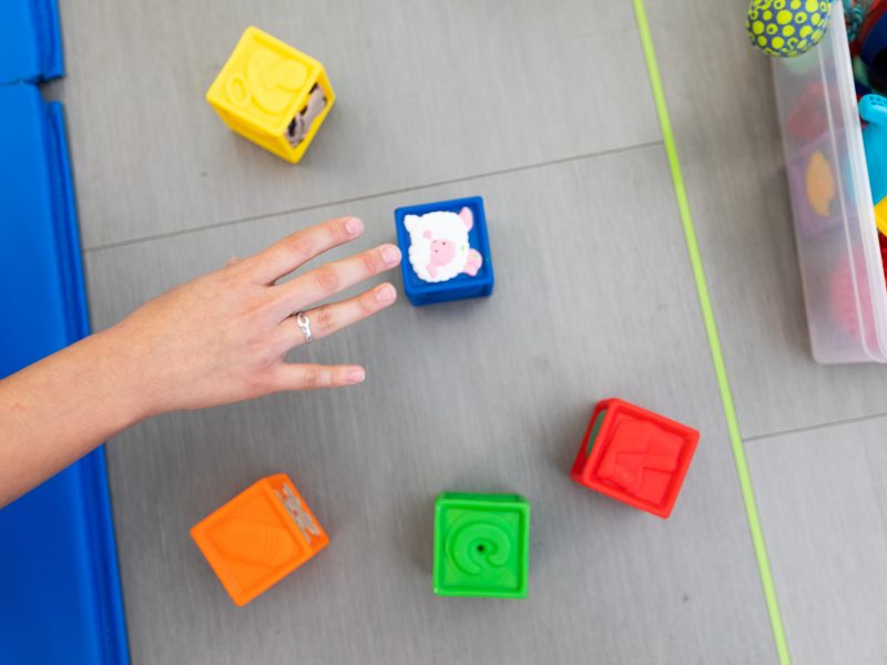 A hand reaches for plastic stacking blocks.