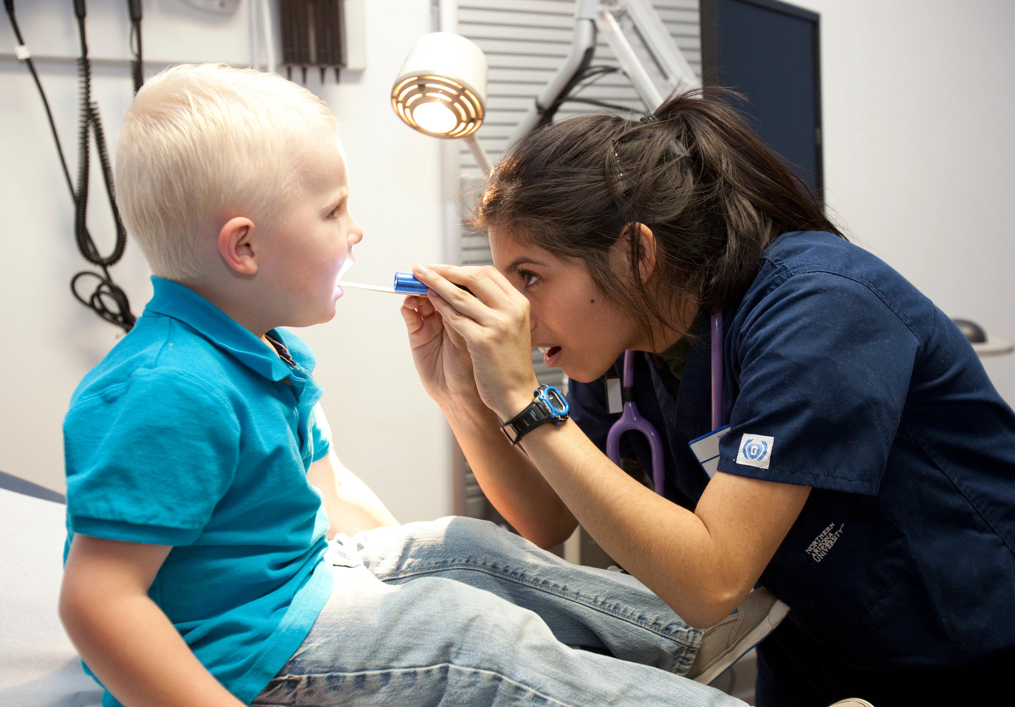 Nurse examining a pediatric patient's mouth.