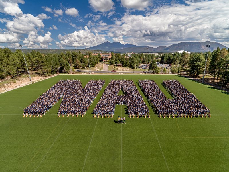Hundreds of people forming the letters "NAU".