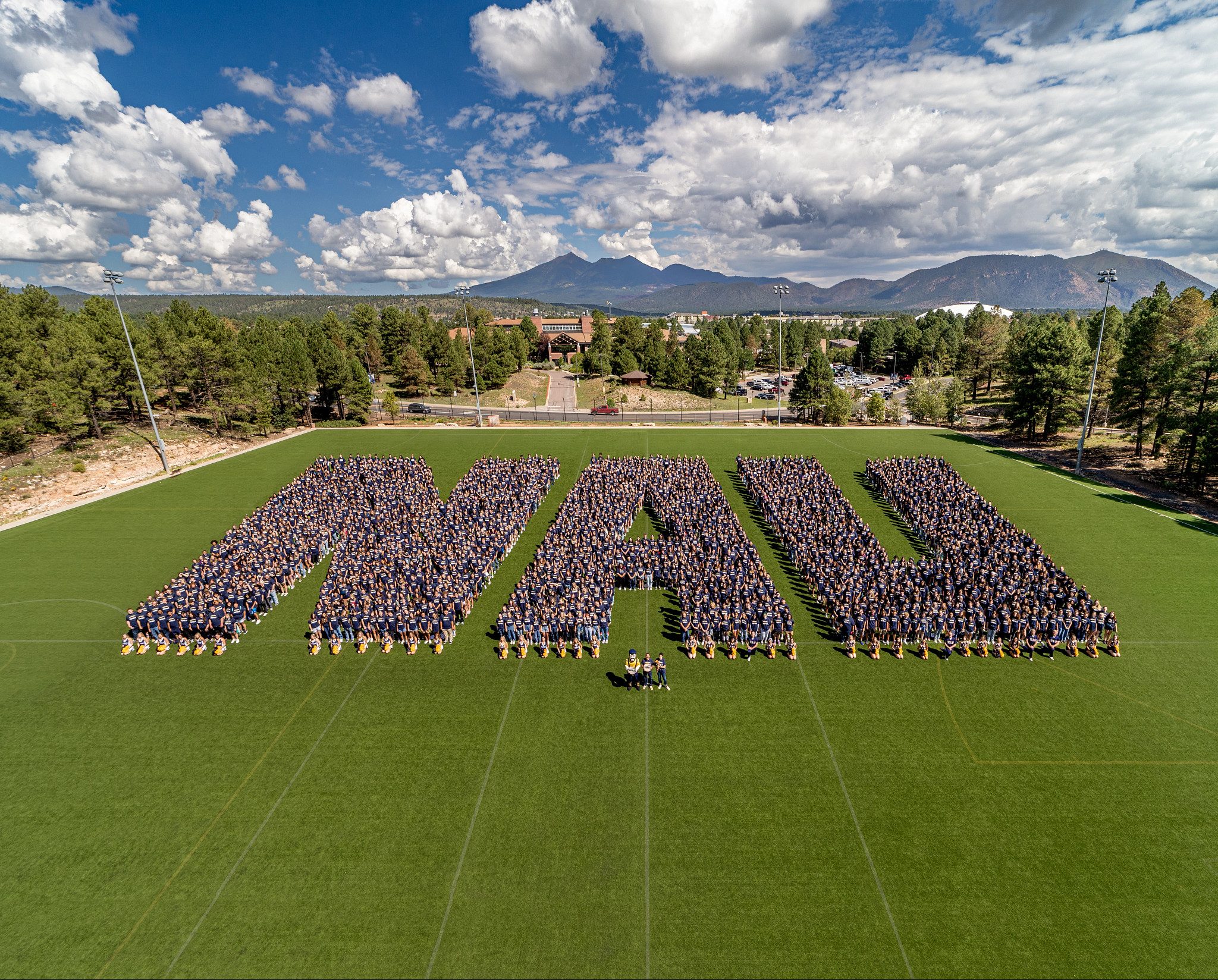 Hundreds of people forming the letters "NAU".