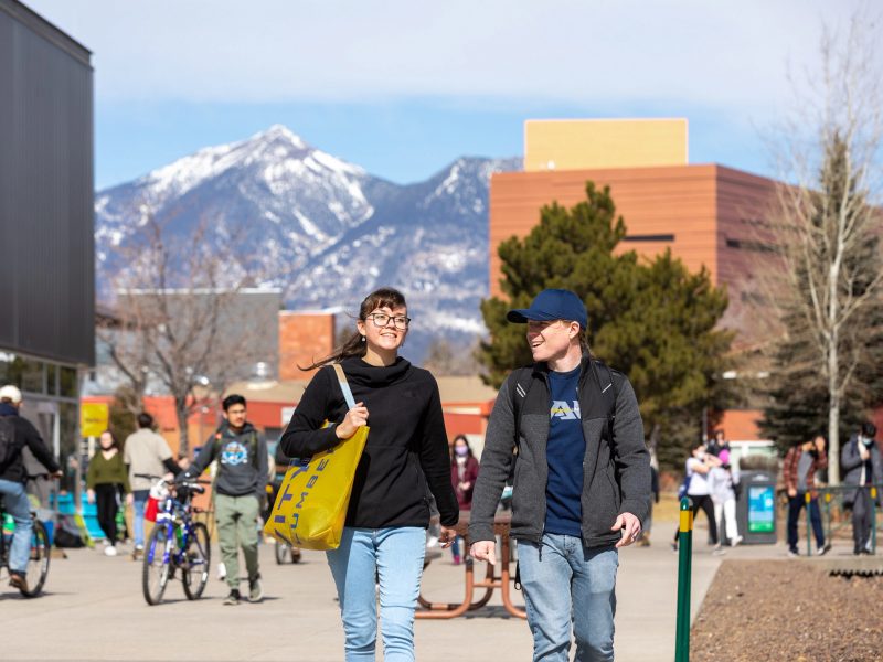 Students walking through campus grounds with mountains in the background.